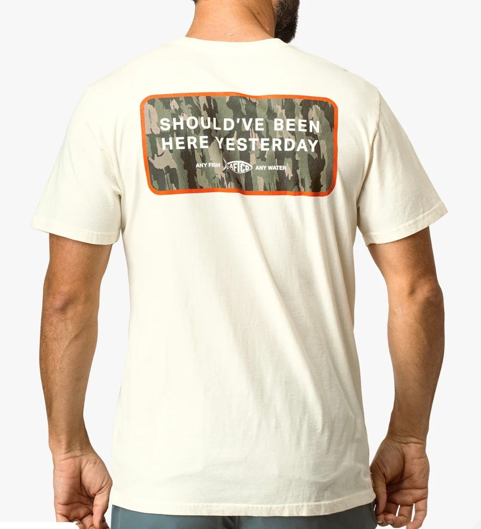 White t-shirt with text on the back worn by a person, against a plain background