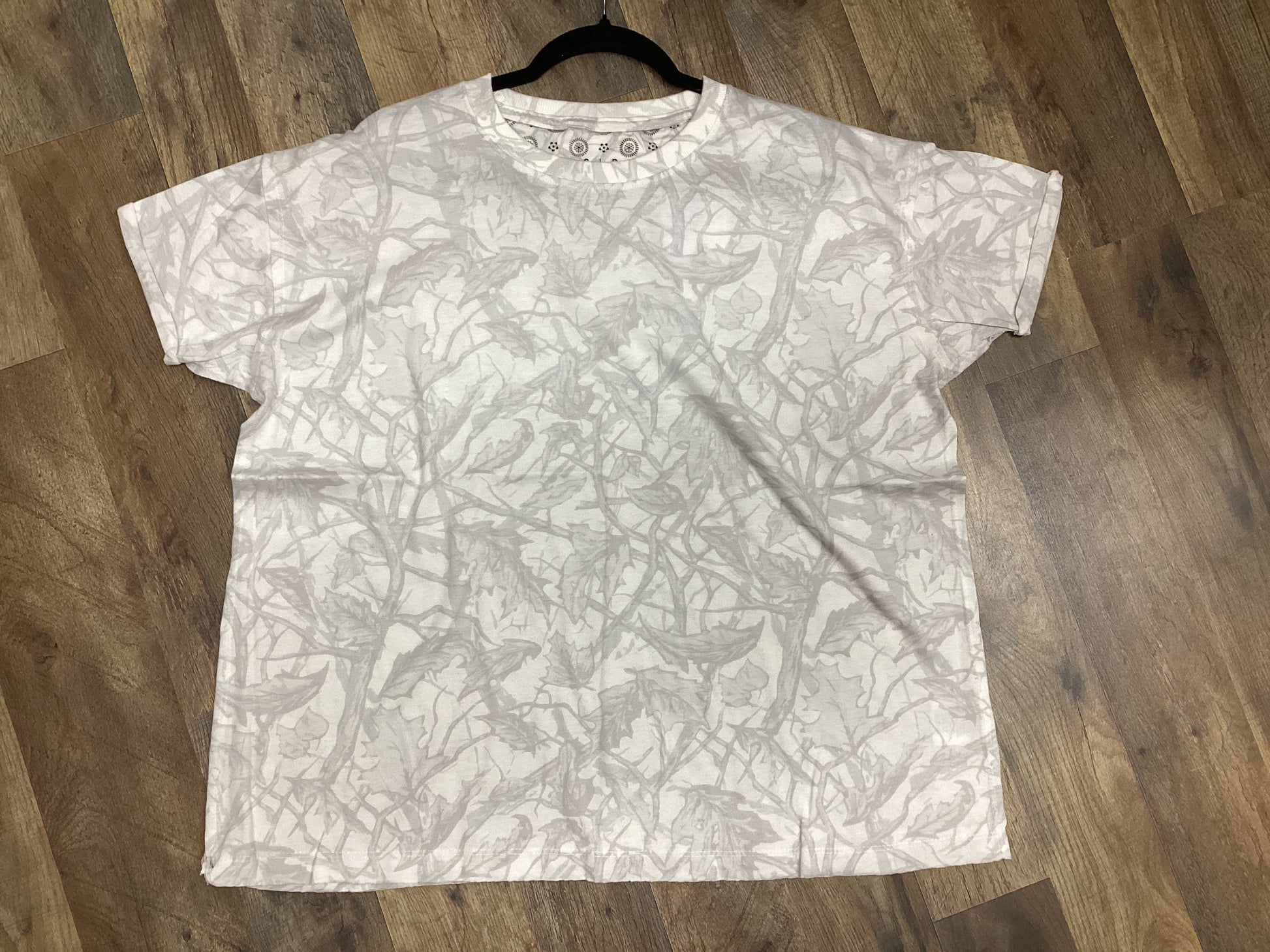 White oversized Ice Woodland camo tee laid flat on a wooden floor