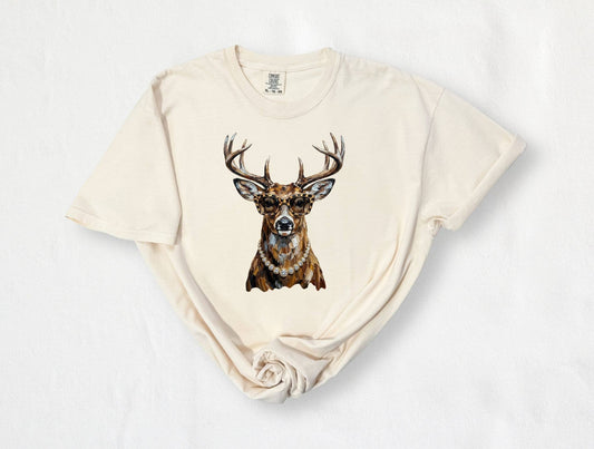 An off-white short-sleeve t-shirt with a graphic print of a brown deer head wearing a gold necklace, laid flat on a white background.