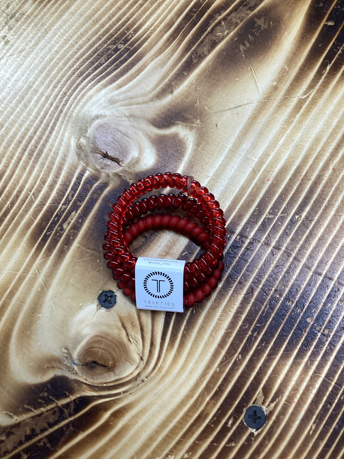Red hair ties on a textured surface with a visible brand logo.