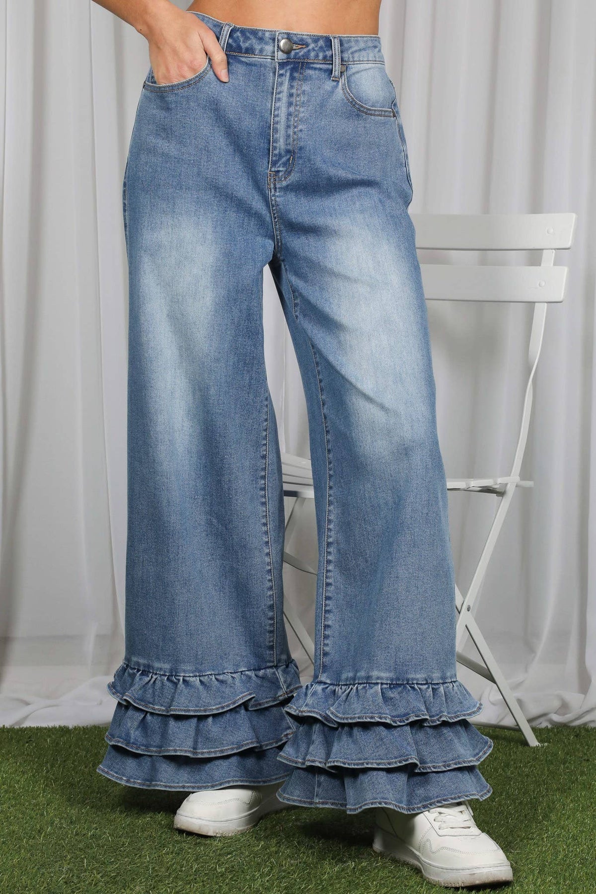 Wide-leg jeans with ruffled bottom worn by a person on a grassy surface.