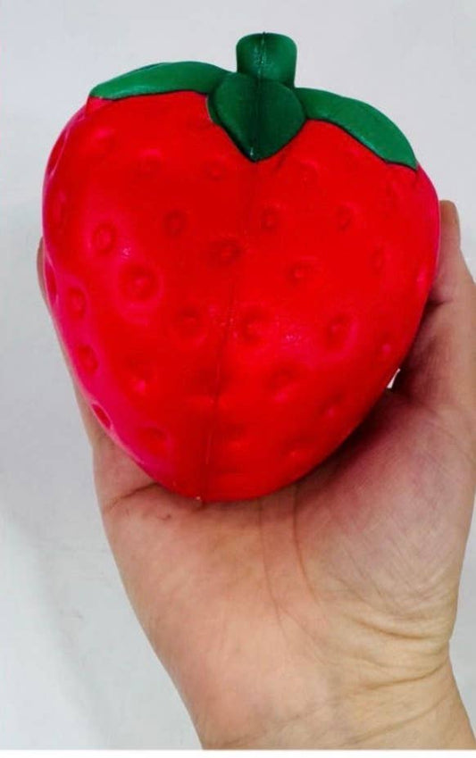 Hand holding a red strawberry-shaped squishy toy against a white background