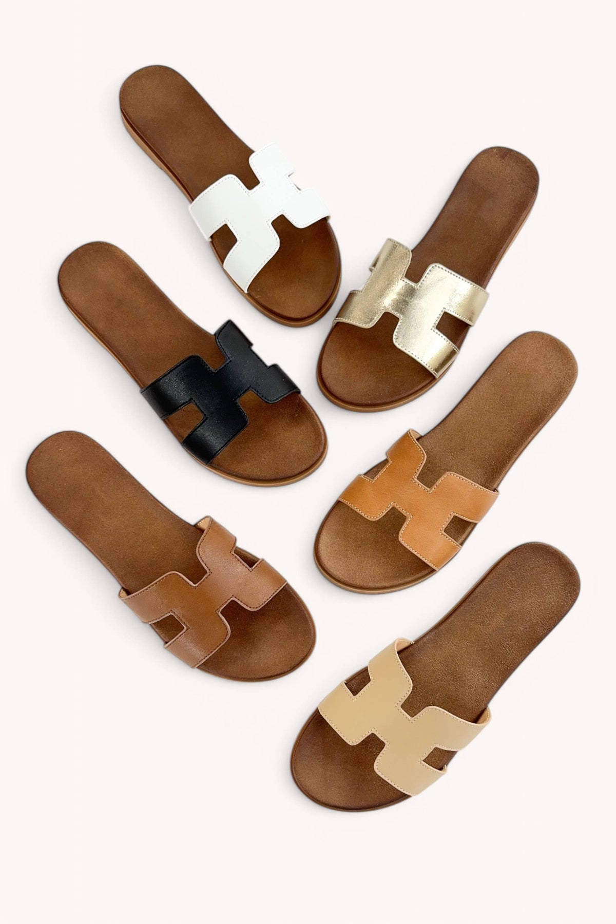 Set of gold sandals with H-shaped straps on a white background