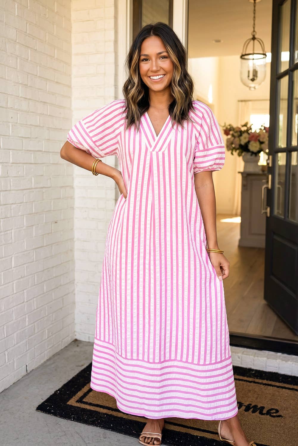 Woman wearing a pink and white striped dress standing in a doorway.
